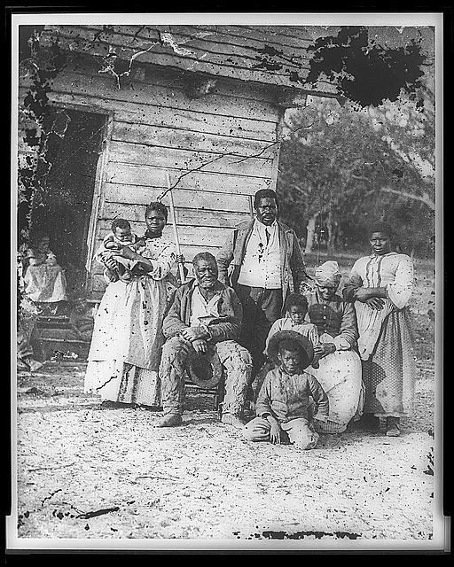 Black and white photograph of an African American enslaved family in front of a home on a plantation