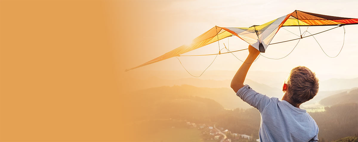 young boy launching a glider into the sky